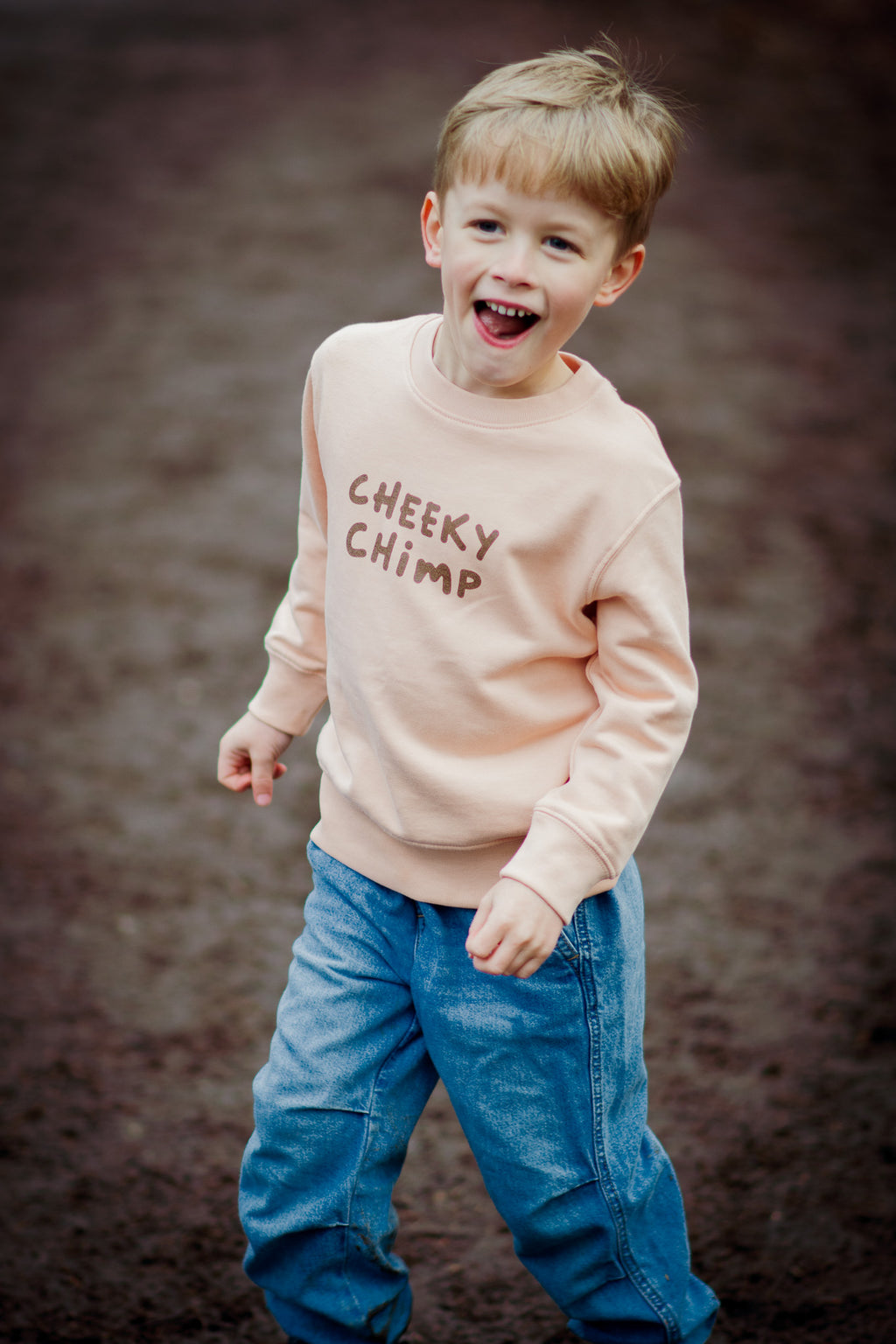 Child wearing a 'Cheeky Chimp' sweater against a brown background
