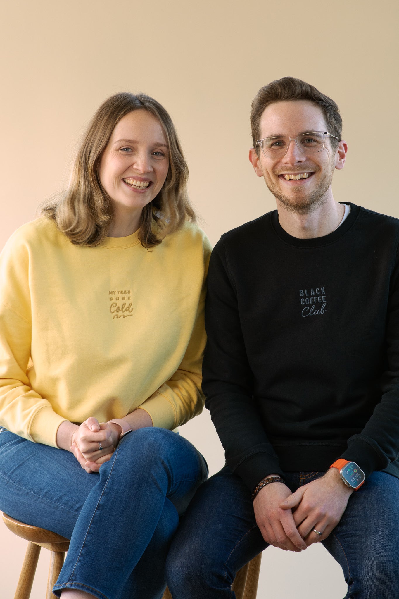 Two people sitting side by side against a plain background