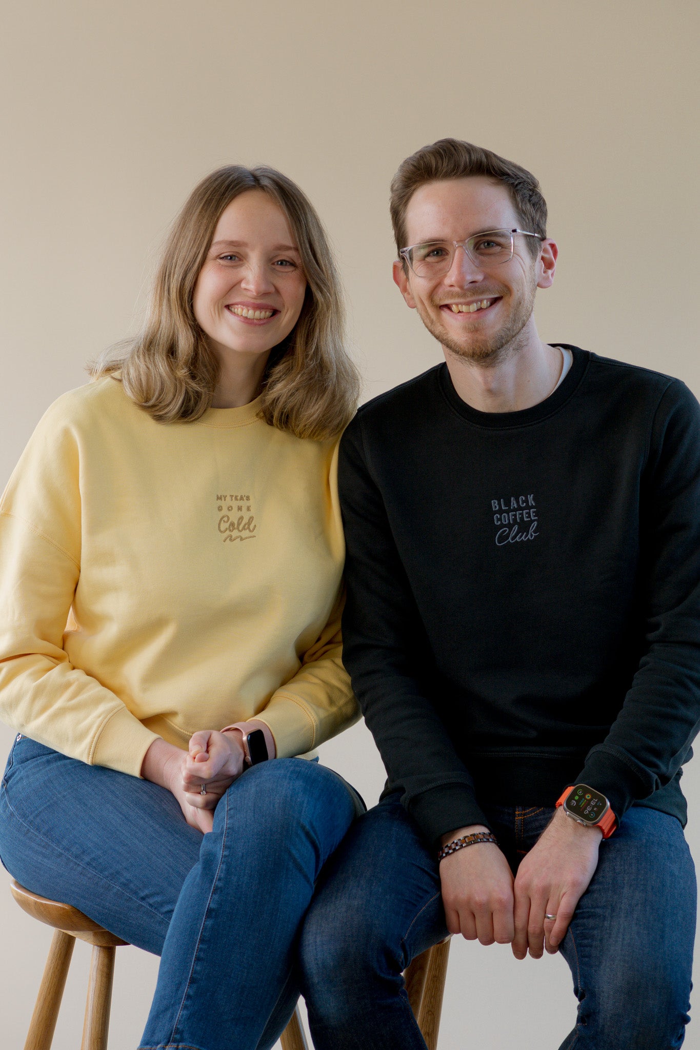Two people sitting together on a plain background