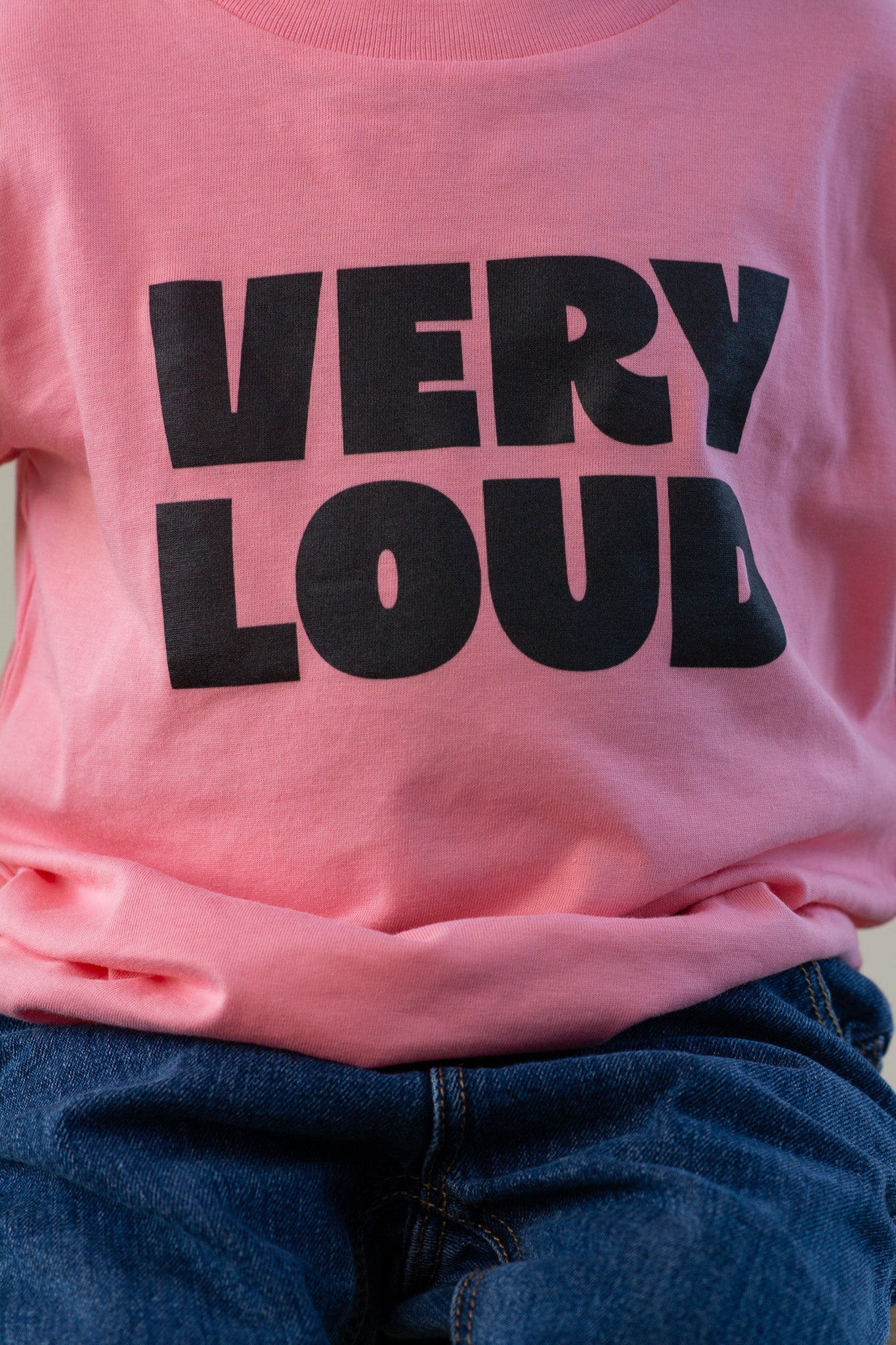 Pink t-shirt with 'VERY LOUD' text in black on a plain background