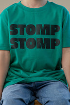 Person wearing a green t-shirt with 'STOMP STOMP' text in black.