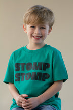 Child wearing a green t-shirt with 'STOMP STOMP' text on a plain background
