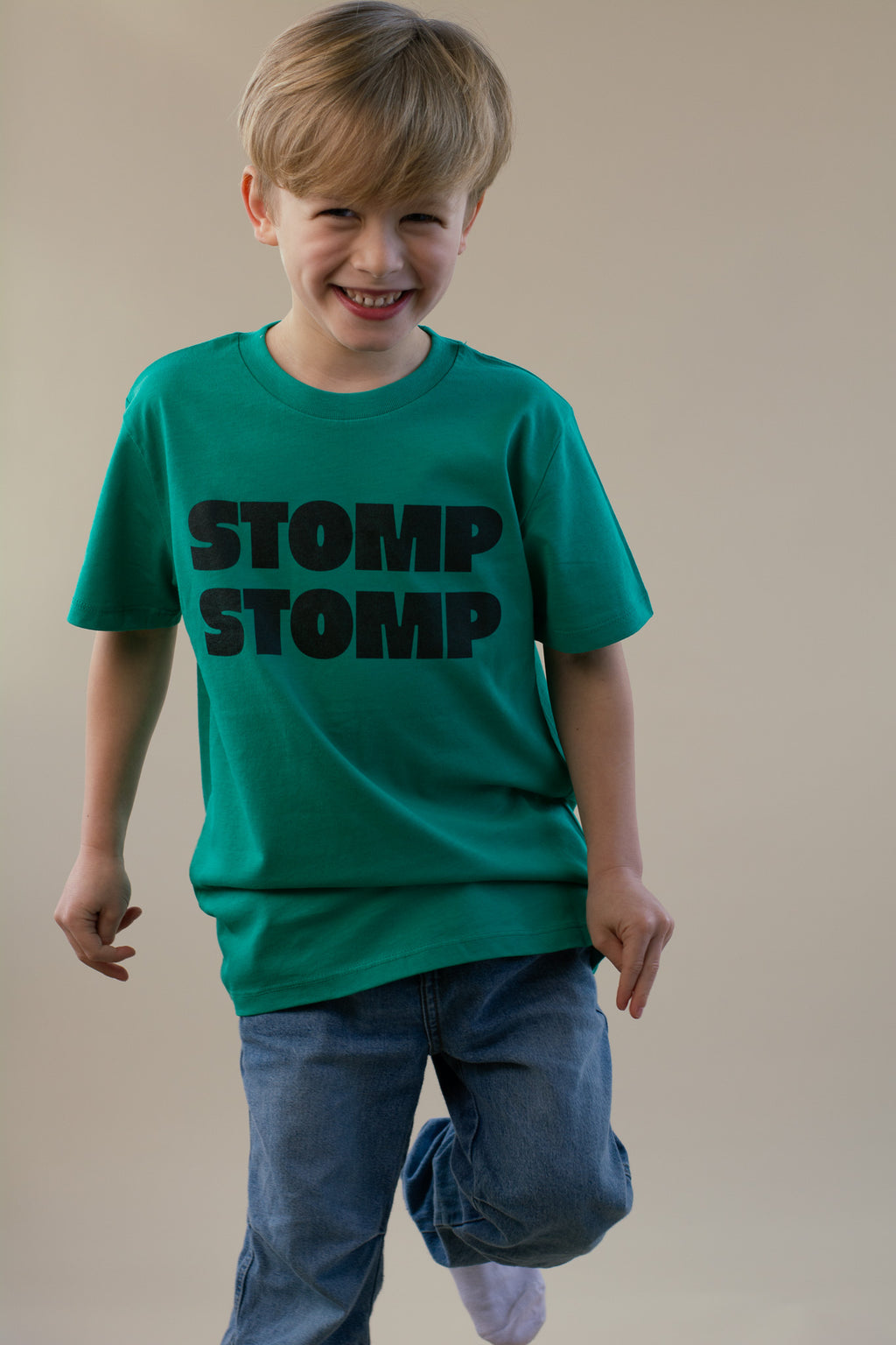 Child wearing a green t-shirt with 'STOMP STOMP' text on a plain background