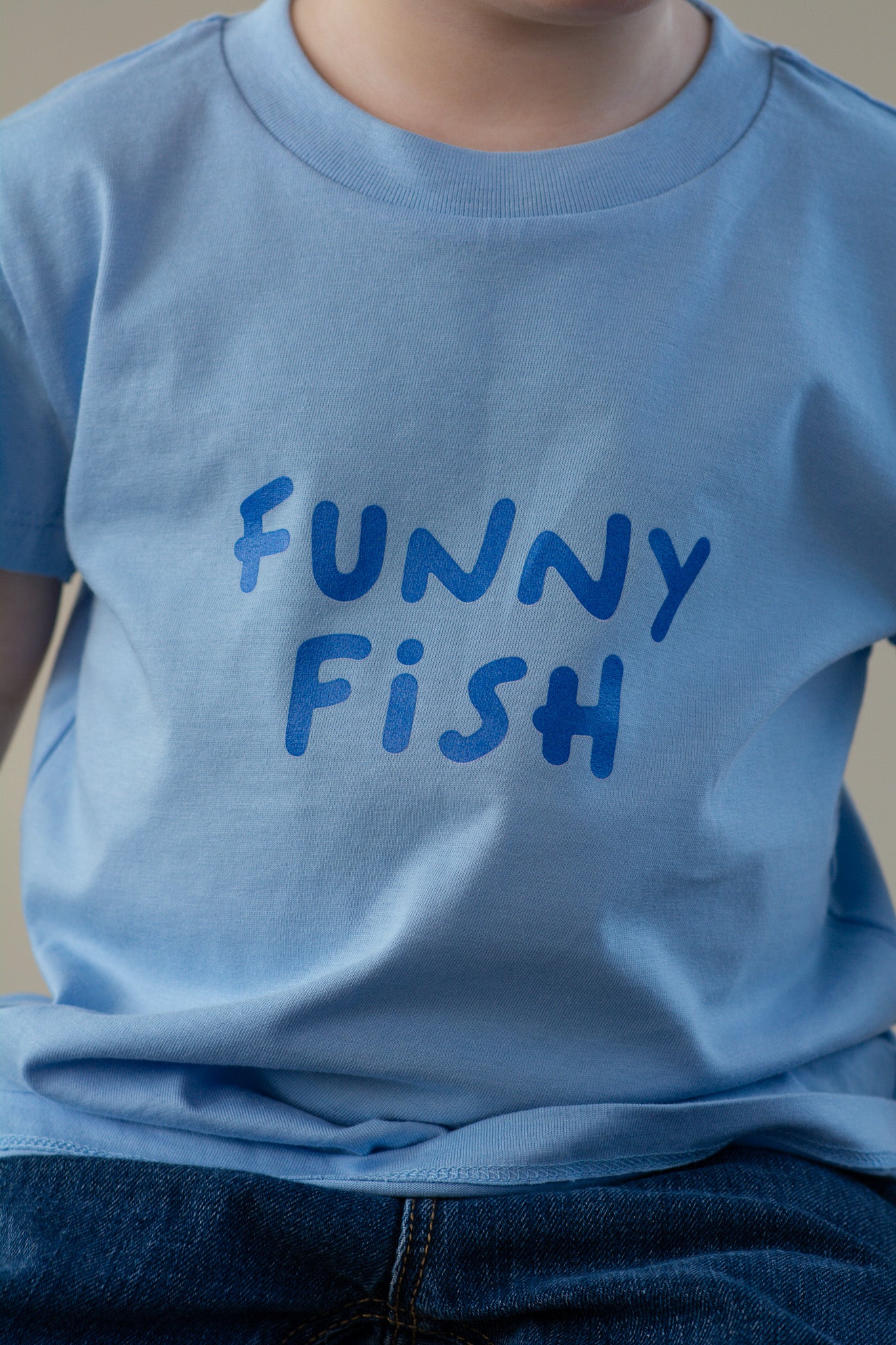 Light blue t-shirt with 'FUNNY FISH' text worn by a person