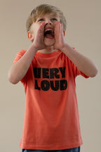 Child wearing a 'VERY LOUD' t-shirt, shouting with hands over mouth