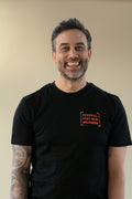 Man wearing a black t-shirt with orange text on a beige background