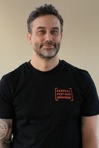 Man wearing a black t-shirt with orange text on a beige background