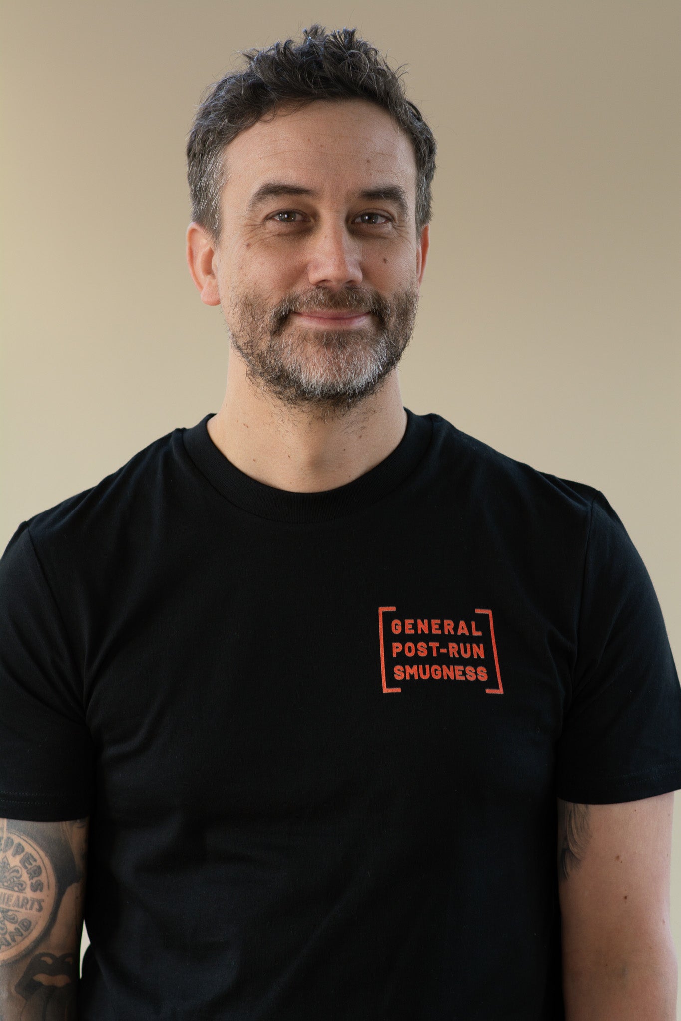 Man wearing a black t-shirt with orange text on a beige background
