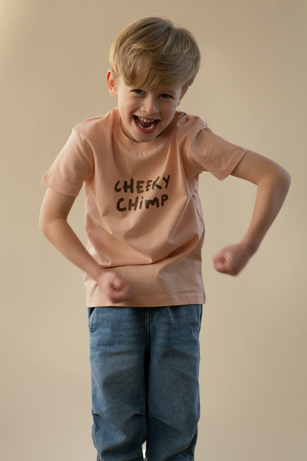 Child wearing a 'Cheeky Chimp' t-shirt on a beige background
