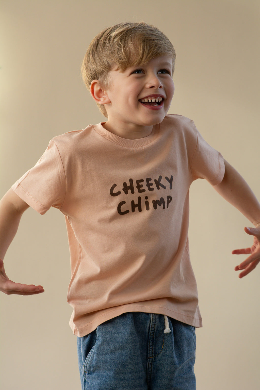Child wearing a 'Cheeky Chimp' t-shirt against a beige background