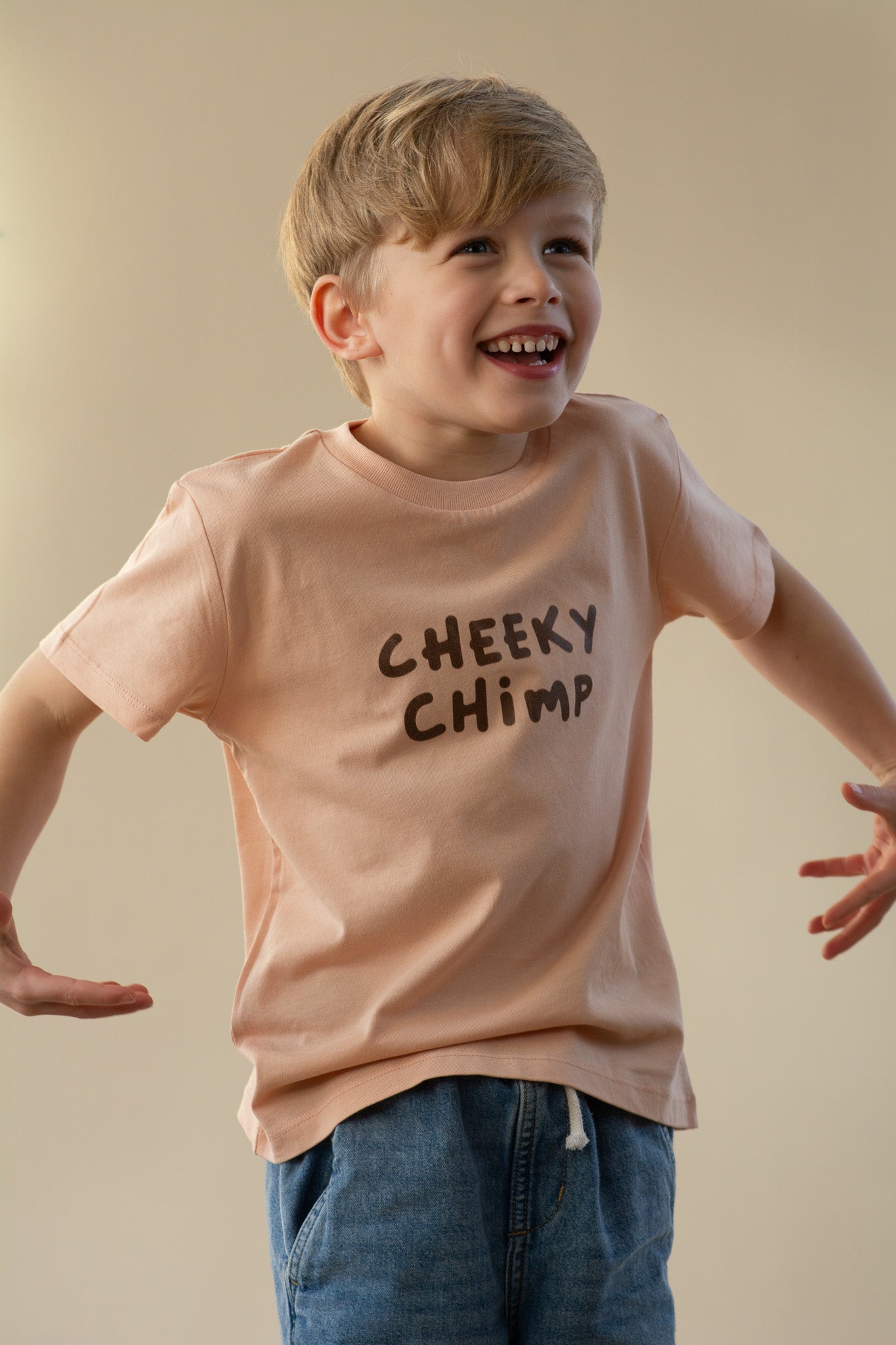 Child wearing a 'Cheeky Chimp' t-shirt against a beige background