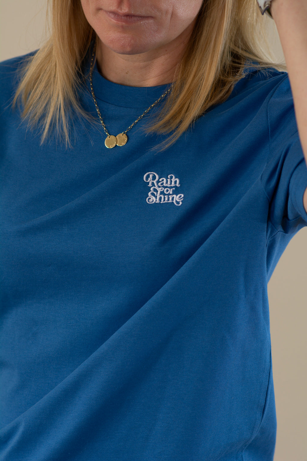 Person wearing a blue t-shirt with 'Rain or Shine' text