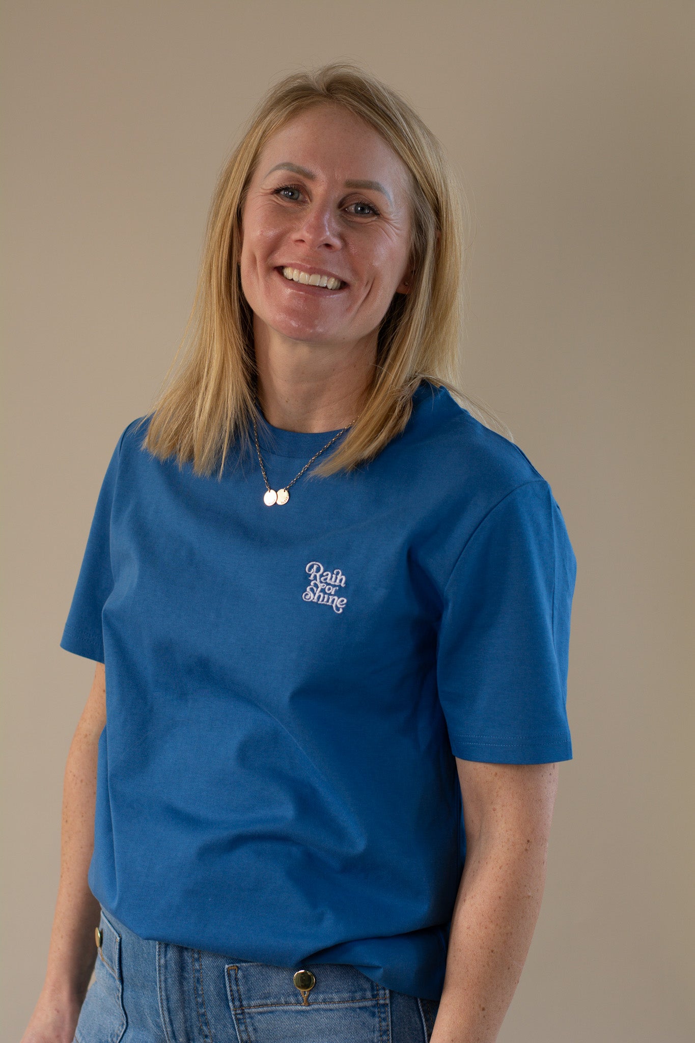 Woman wearing a blue t-shirt with a logo on a beige background