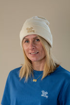Person wearing a beige beanie and blue shirt with 'Rain of Shine' branding on a beige background