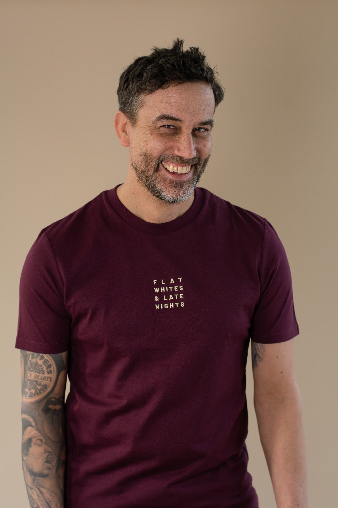 Man wearing a maroon t-shirt with text on a beige background