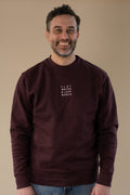 Man wearing a maroon sweatshirt with 'FLAT WHITES & LATE NIGHTS' text on a beige background