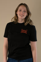 Person wearing a black t-shirt with a orange logo on a beige background