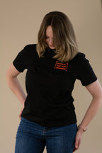 Woman wearing a black t-shirt with orange text on a beige background