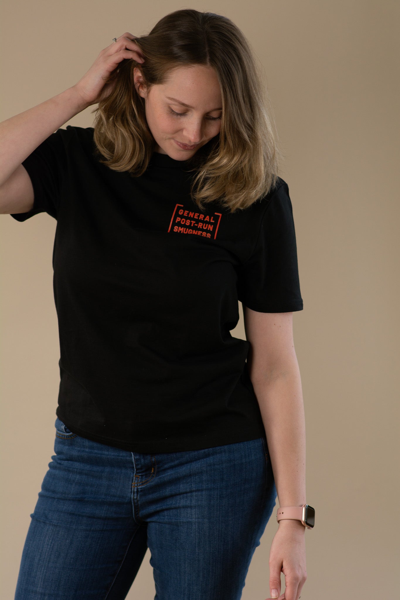 Person wearing a black t-shirt with a orange logo on a beige background