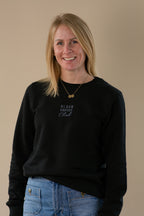 Woman wearing a black sweatshirt with 'Black Coffee Club' text on a beige background