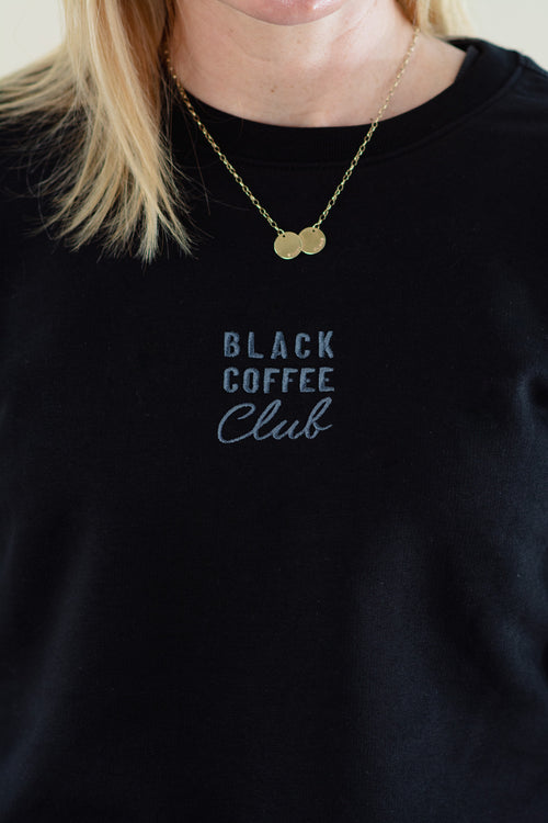 Black sweatshirt with 'Black Coffee Club' text and a gold necklace worn by a person