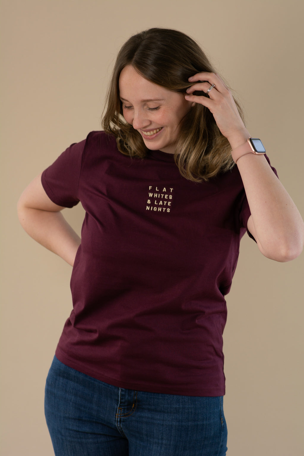 Woman wearing a maroon t-shirt with text on a beige background