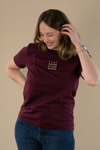 Woman wearing a maroon t-shirt with text on a beige background