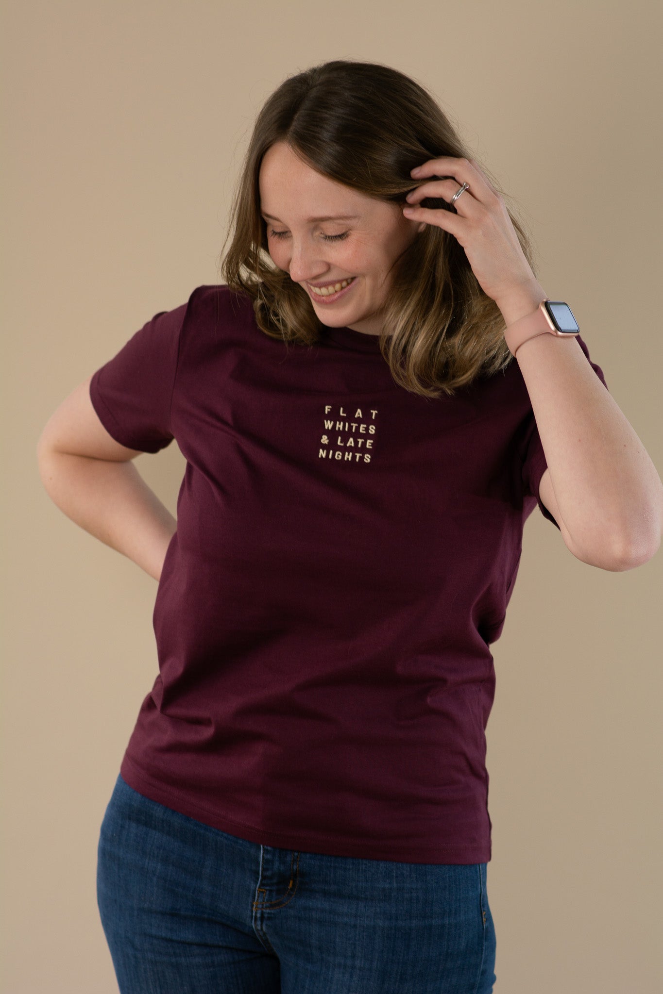Woman wearing a maroon t-shirt with text on a beige background