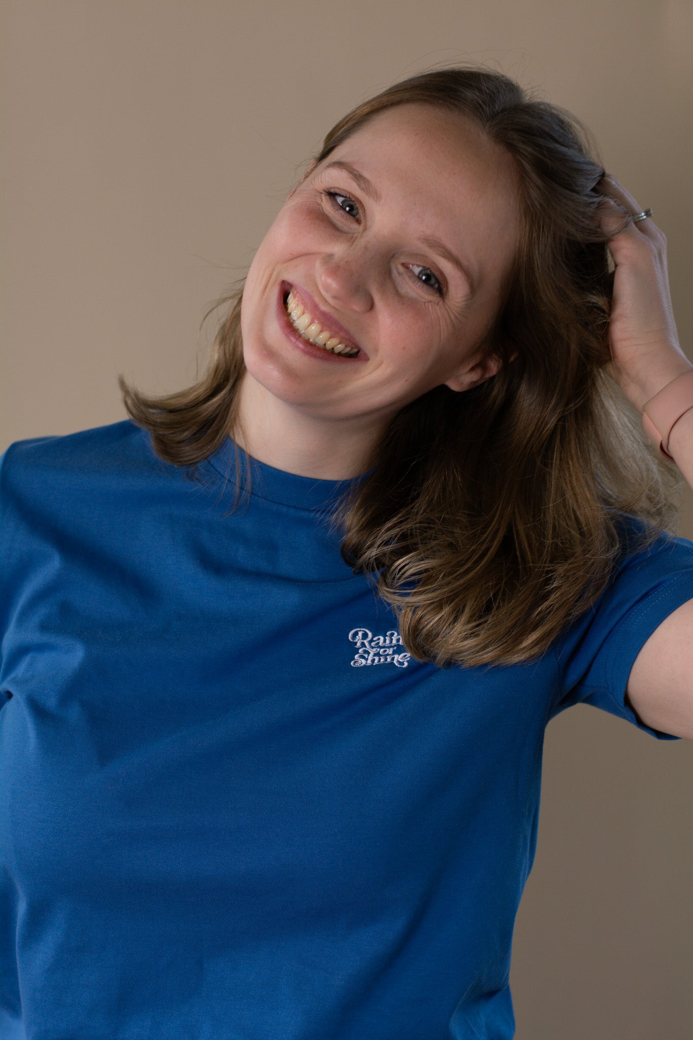 Person wearing a blue t-shirt with a logo, posing against a plain background