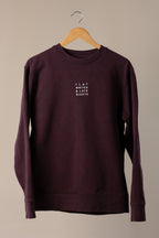 Maroon sweatshirt with 'FLAT WHITES & LATE NIGHTS' text on a hanger against a beige background