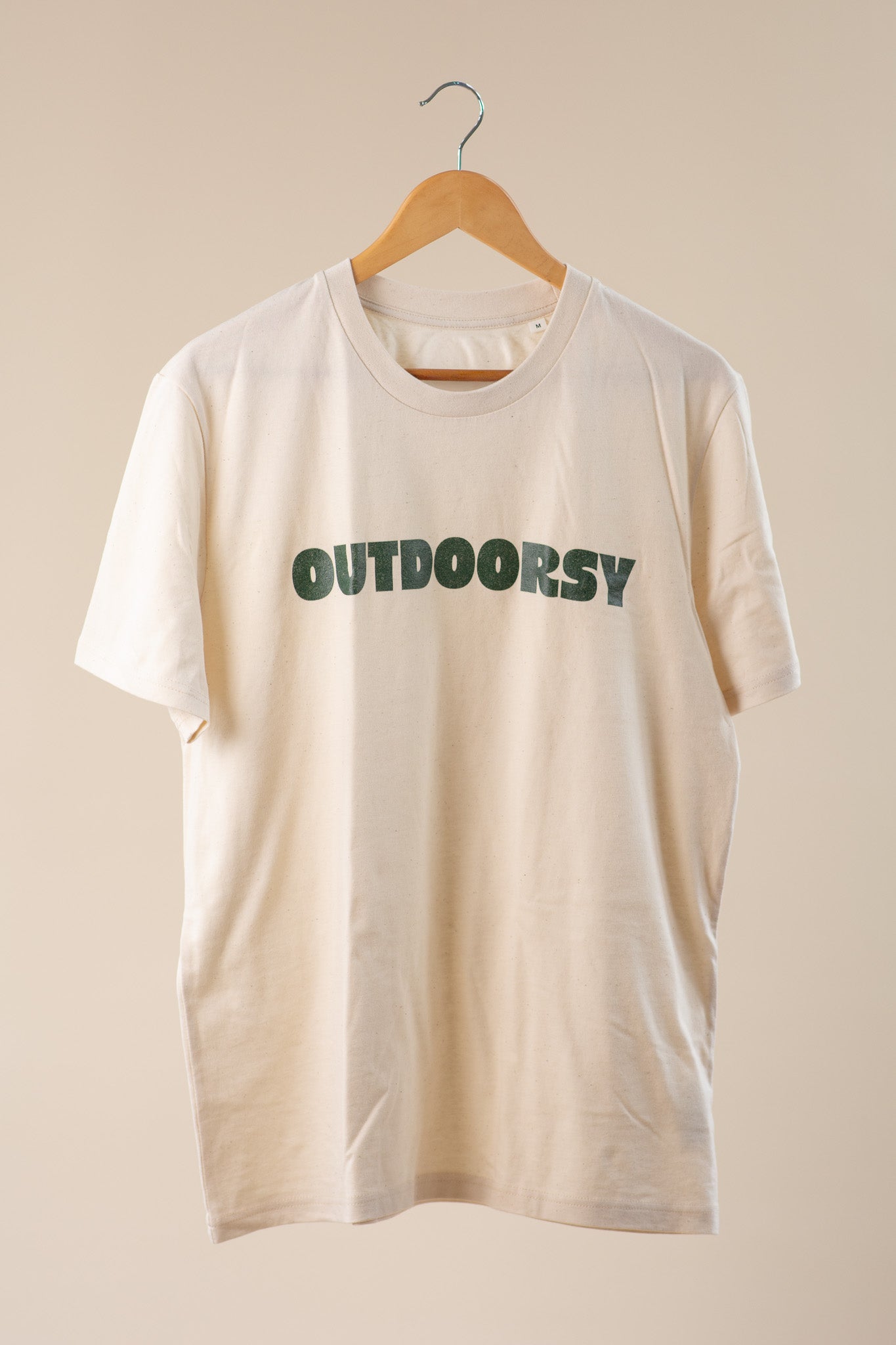 Beige t-shirt with 'OUTDOORSY' text on a beige background