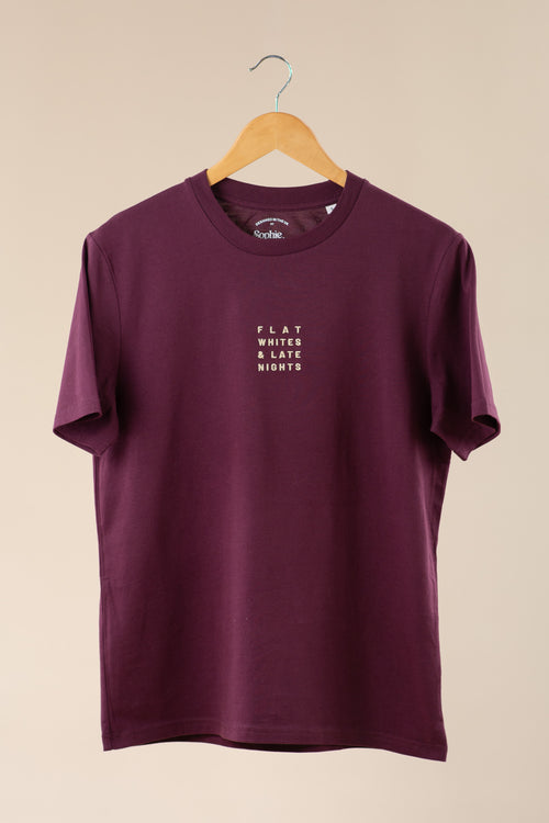 Maroon t-shirt with text on a hanger against a beige background