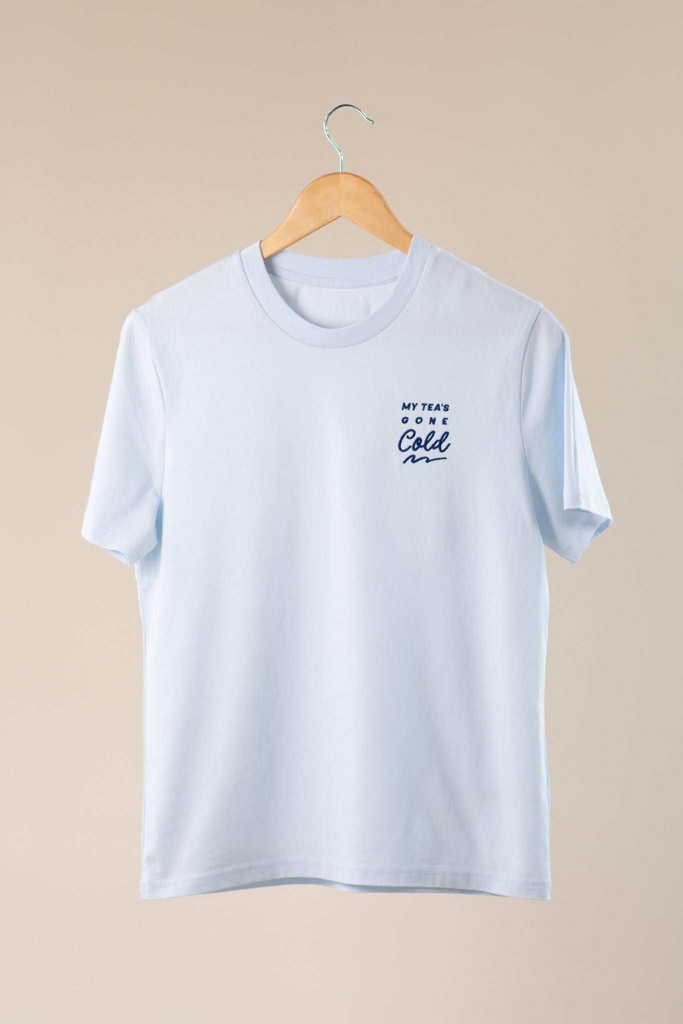 Blue t-shirt with 'My Tea's Gone Cold' text on a beige background