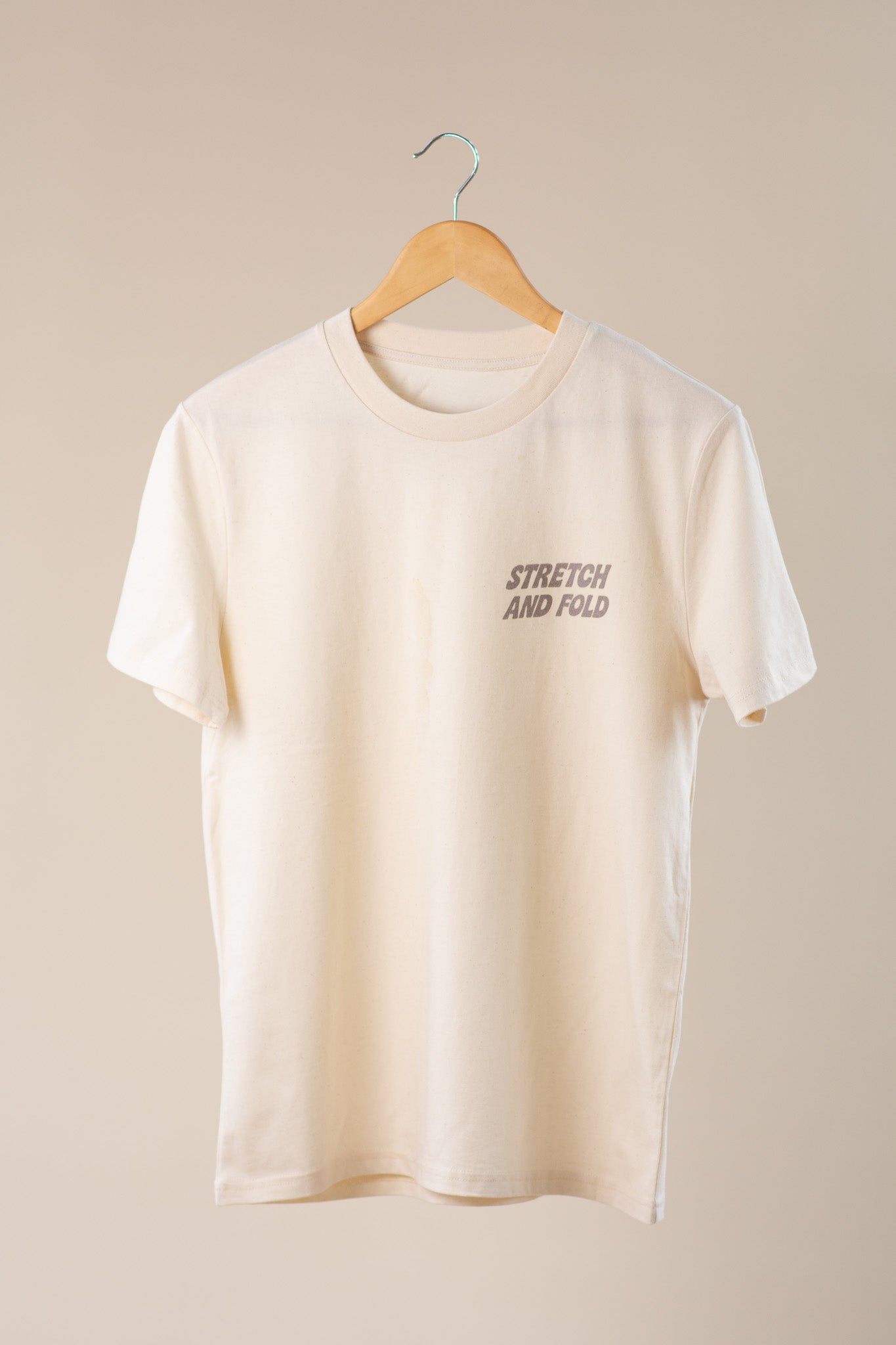 Beige t-shirt with 'Stretch and Fold' text on a beige background