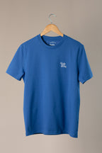 Blue t-shirt with a logo on a wooden hanger against a beige background