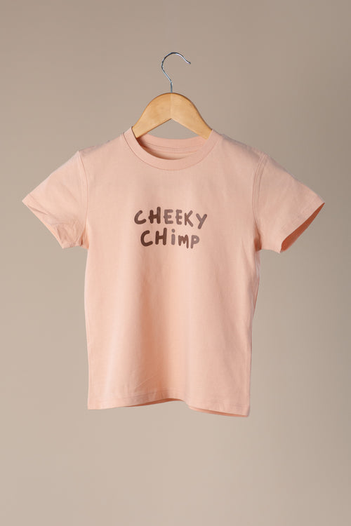 Peach t-shirt with 'Cheeky Chimp' text on a wooden hanger against a beige background