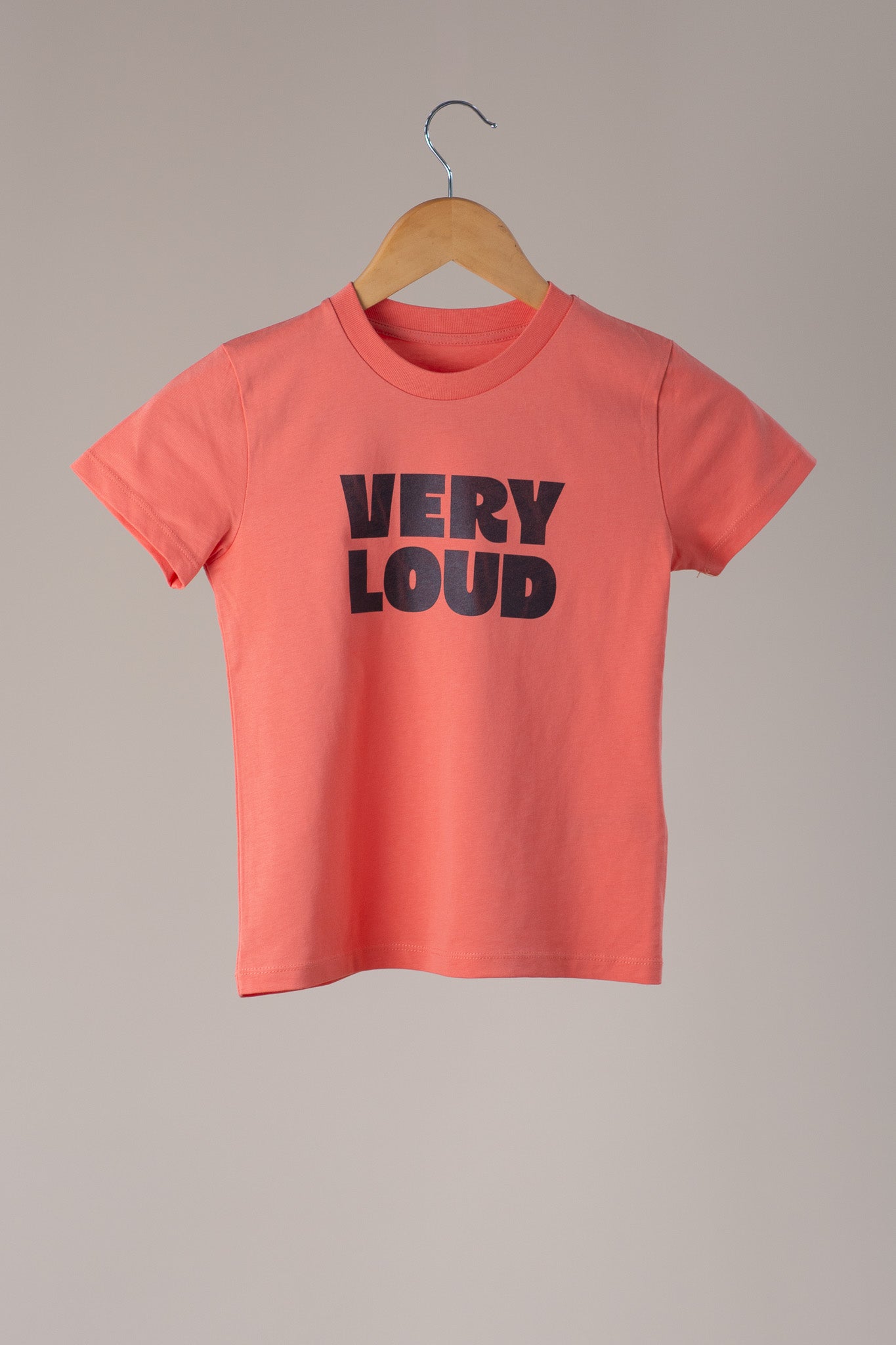 Orange t-shirt with 'VERY LOUD' text on a wooden hanger against a grey background