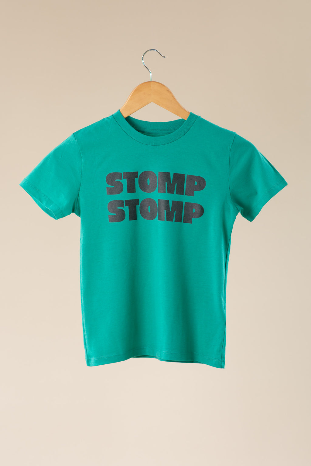 Green t-shirt with 'STOMP STOMP' text on a beige background