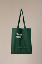Green tote bag with 'Library books' text on a beige background