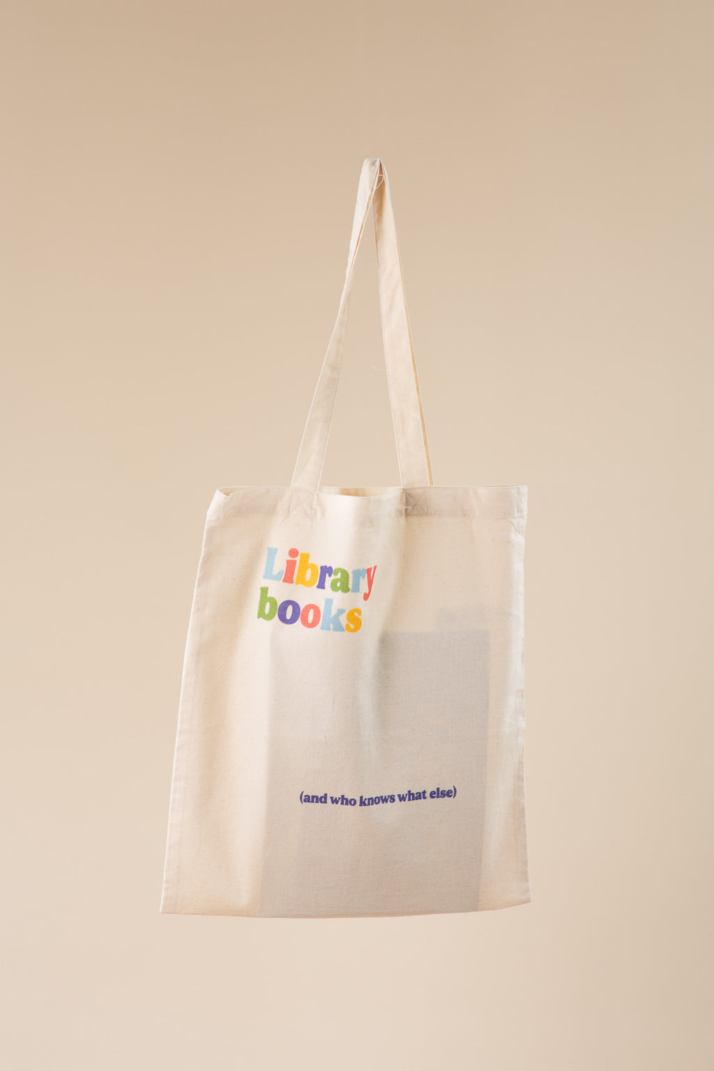 Beige tote bag with 'library books' text on a beige background