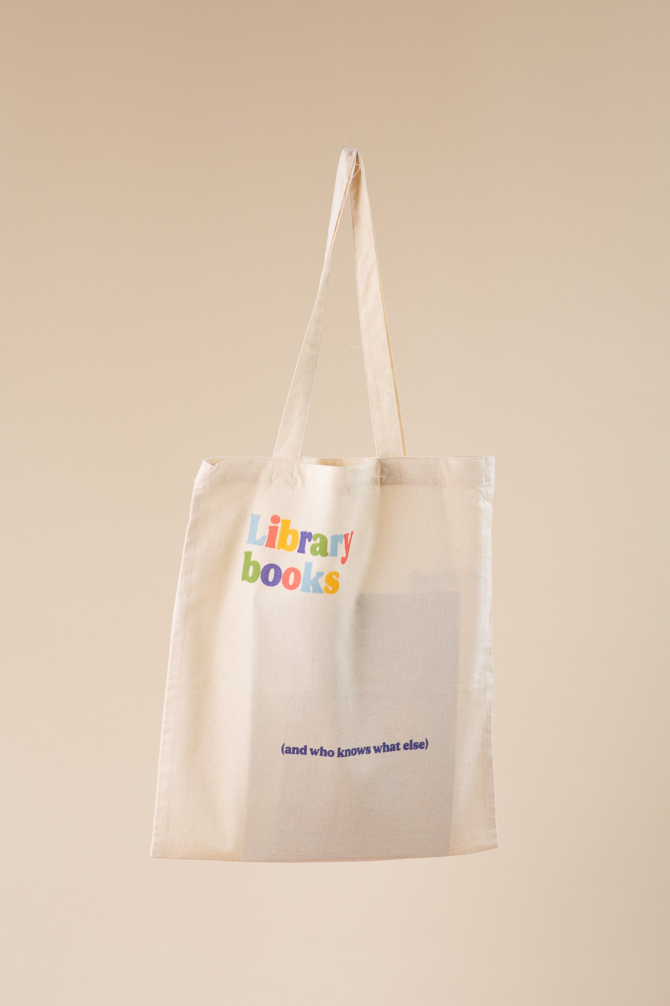 Beige tote bag with 'library books' text on a beige background