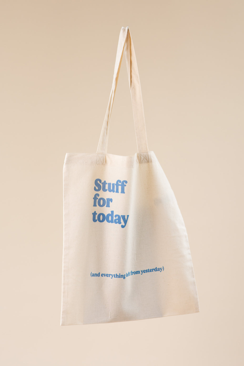 Beige tote bag with blue text on a beige background