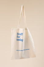 Beige tote bag with blue text on a beige background