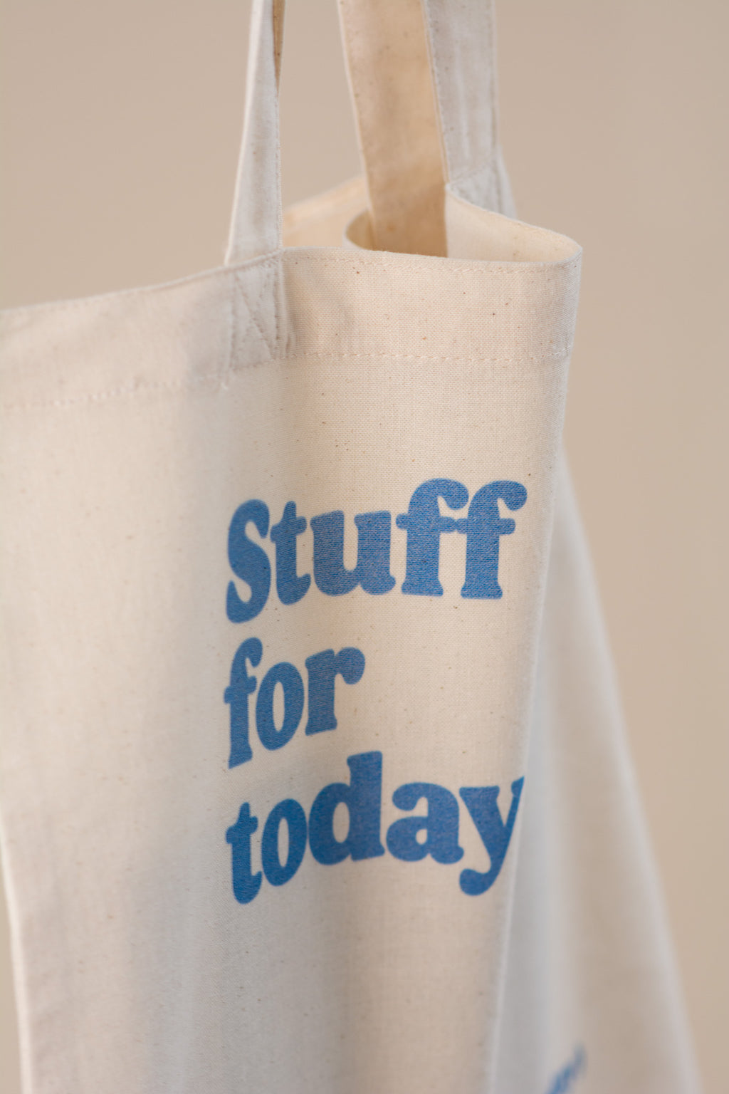 White tote bag with blue text 'Stuff for today' on a beige background