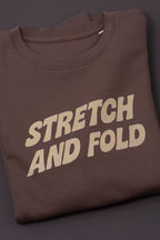 Brown t-shirt with 'STRETCH AND FOLD' text on a dark background