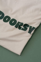 Close-up of a white fabric with 'OUTDOORSY' printed in green on a green background
