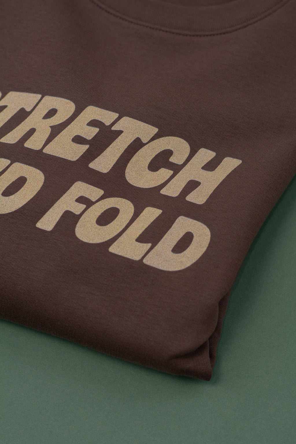 Brown sweatshirt with 'STRETCH AND FOLD' text on a green background