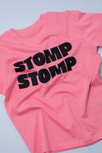 Pink t-shirt with 'STOMP STOMP' text on a light grey background