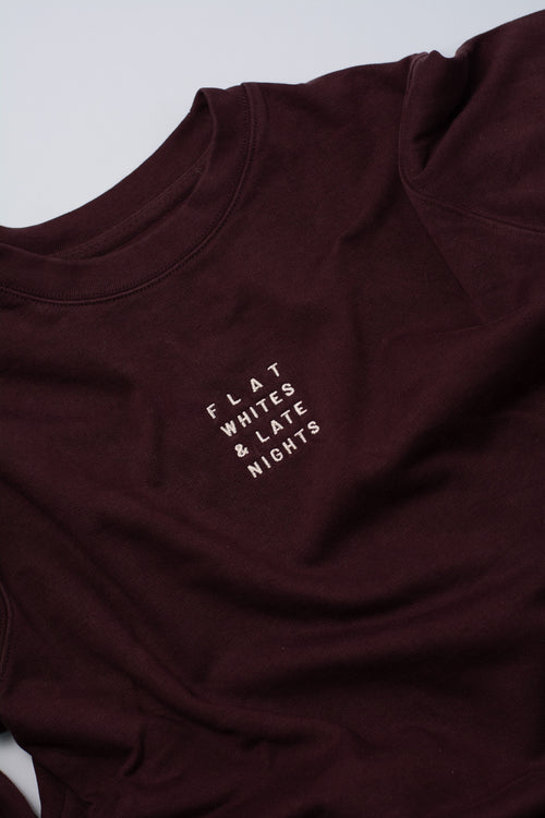 Maroon sweatshirt with text 'FLAT WHITES & LATE NIGHTS' on a light grey background