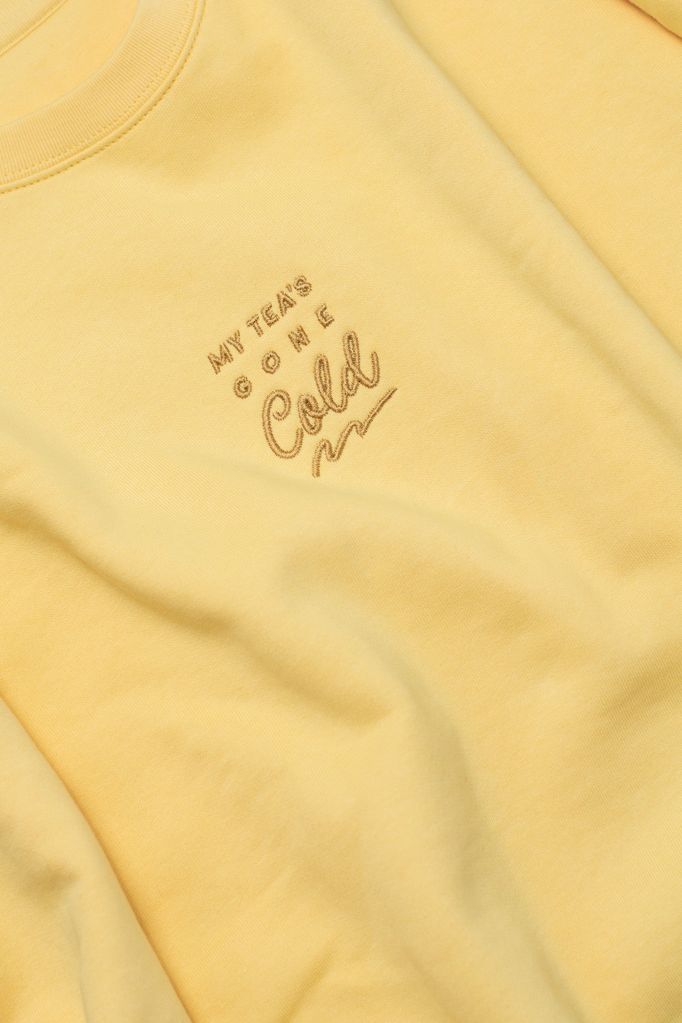 Yellow sweatshirt with embroidered text on a yellow background